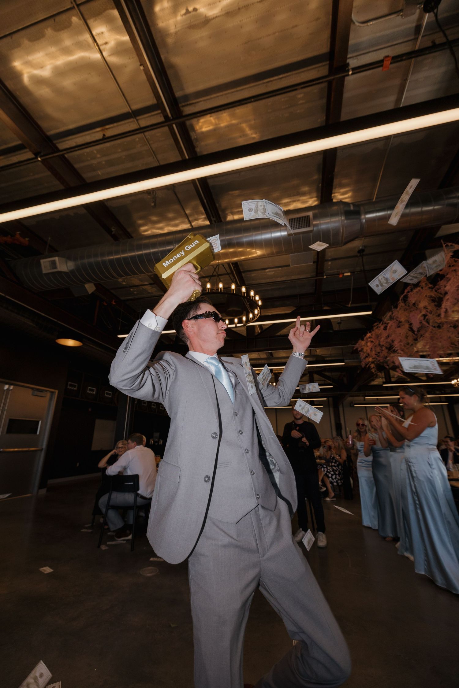 Person in light gray suit dances and throws paper money in the air during what appears to be a celebration event.