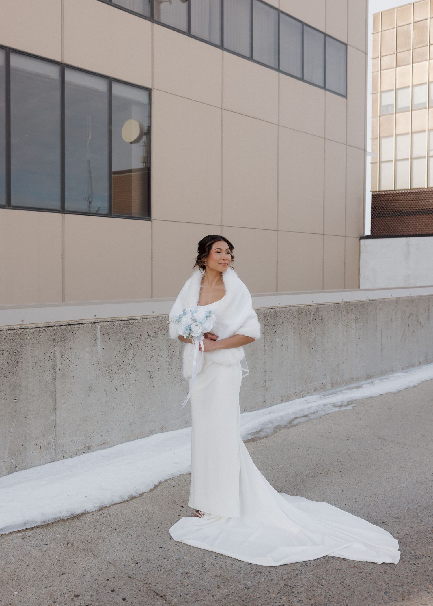 A bride in a flowing white wedding dress poses against a concrete wall in a series of elegant portraits.