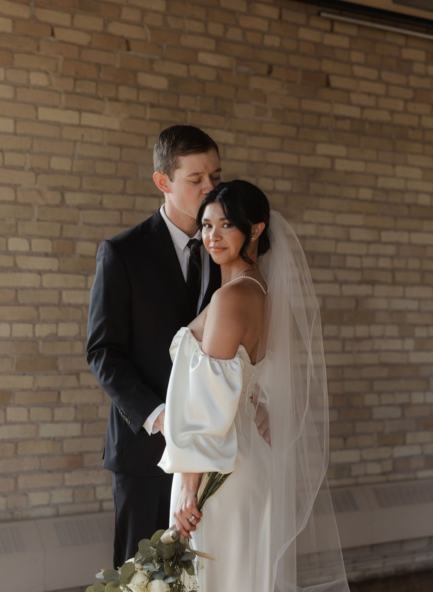 A romantic wedding moment captured in a series of five photos against a brick wall backdrop.