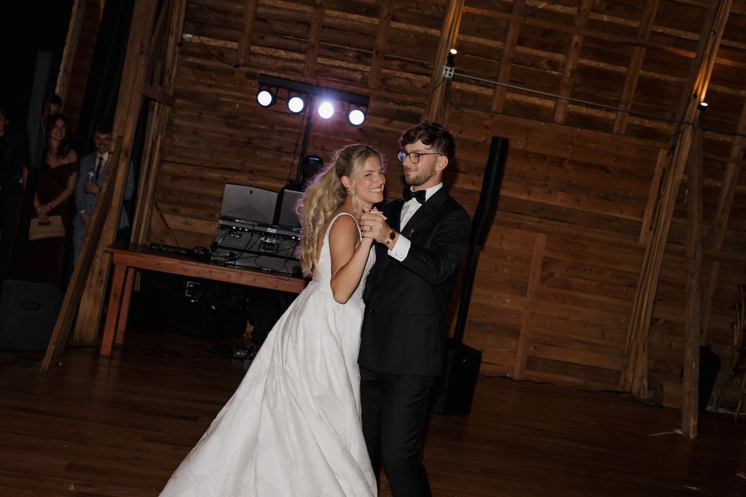 A couple shares a romantic dance together in a rustic wooden barn venue during a wedding celebration.