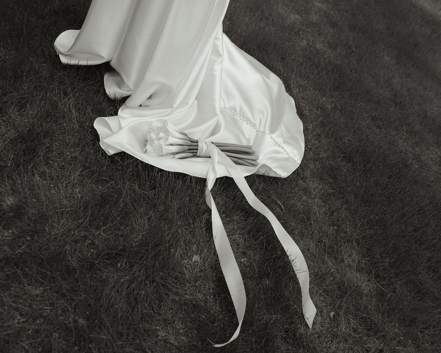 Black and white photograph showing graceful movement of a dancer in a flowing white dress against a dark background.