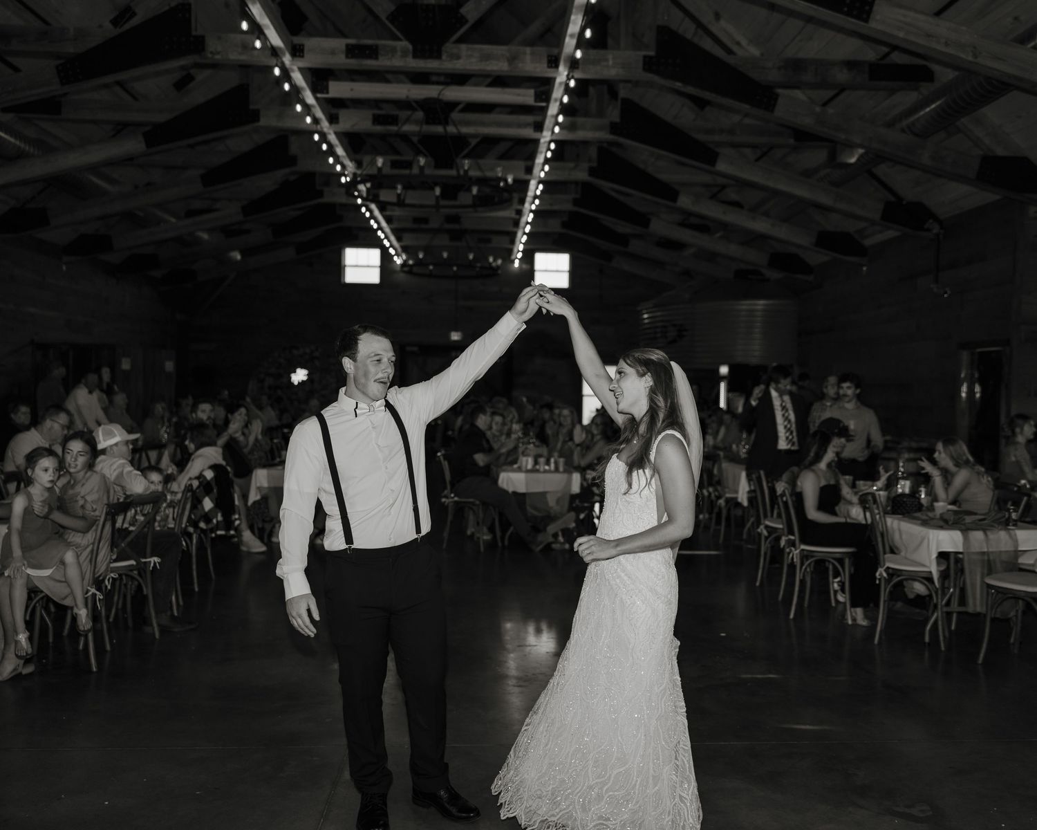Black and white photos show couples dancing at a wedding reception in a rustic venue with string lights overhead.