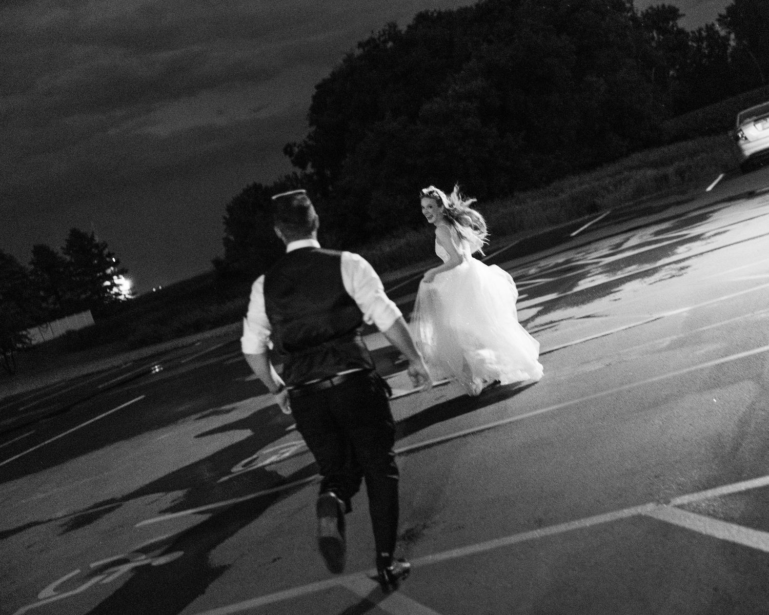 A black and white panoramic sequence shows a couple walking through a parking lot on their wedding day.