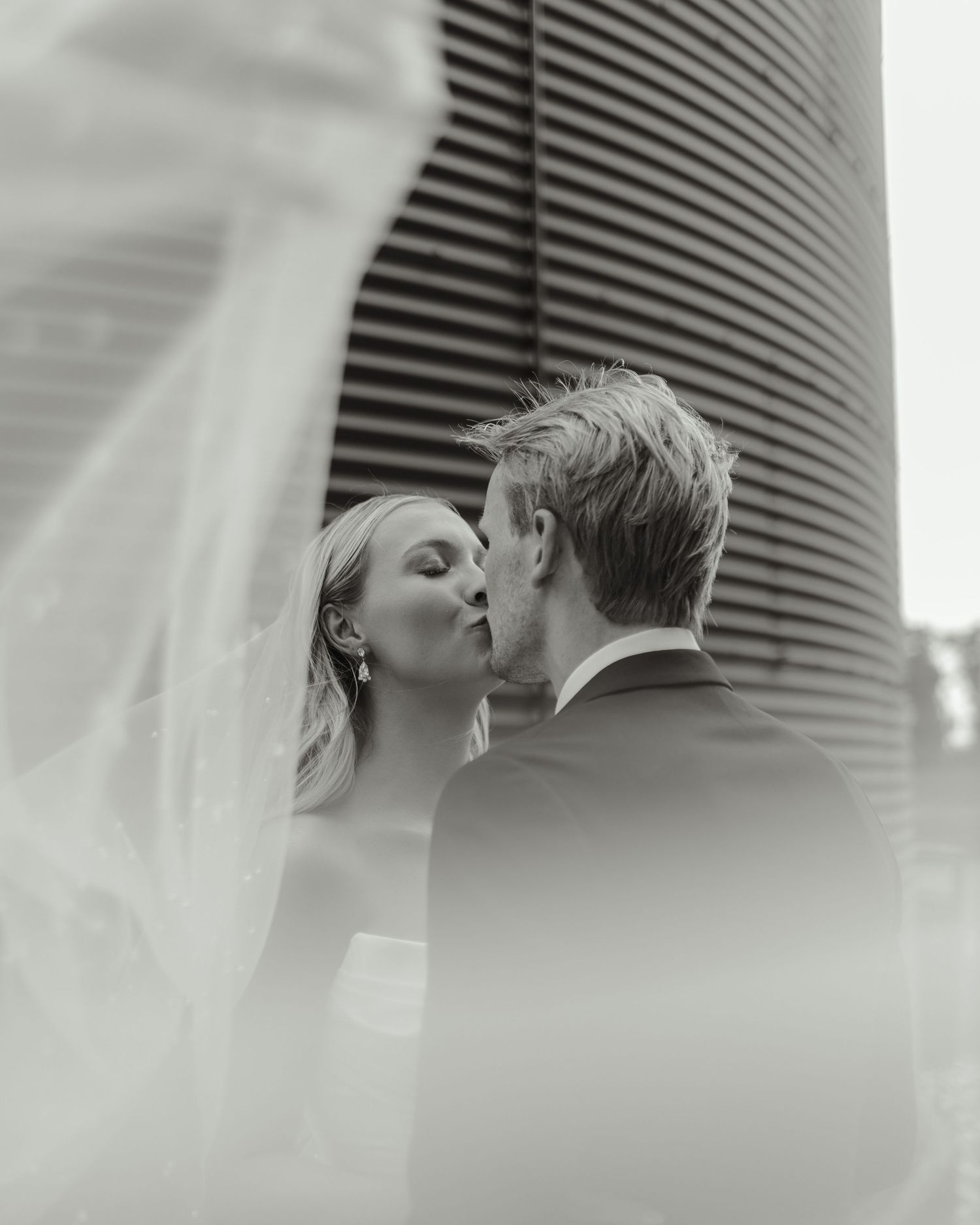 An intimate black and white portrait capturing a tender kiss between newlyweds.
