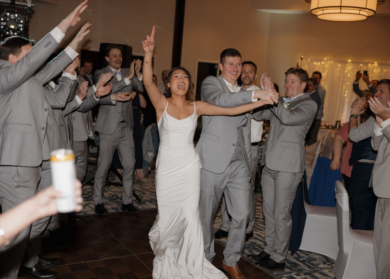 Wedding guests dance in a line formation at a reception while following choreographed moves on the dance floor.