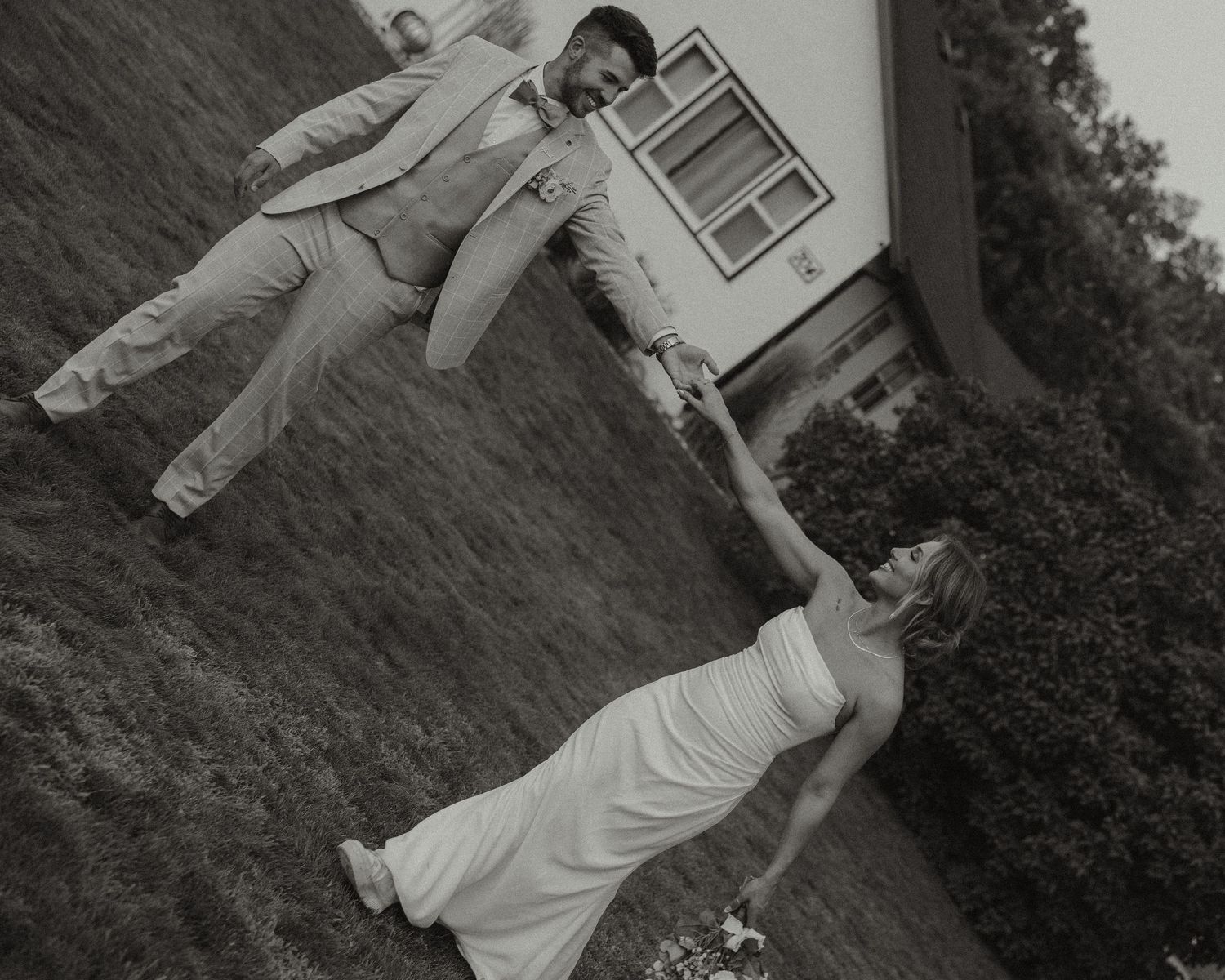 Wedding couple posing playfully outdoors in black and white photography.