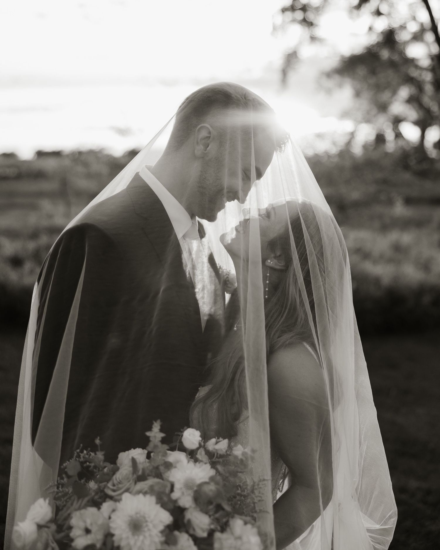 Black and white wedding photo series showing tender moments between a bride and groom through a flowing veil.