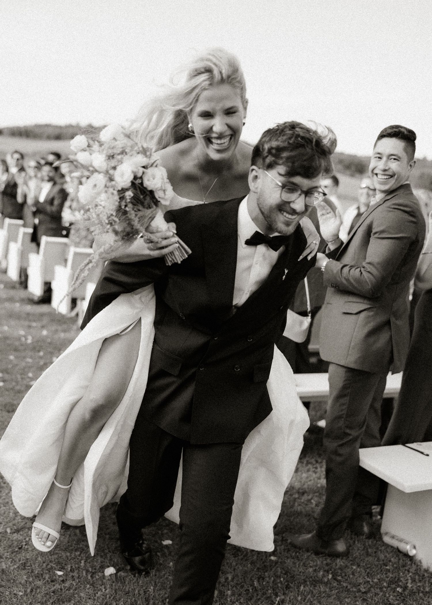 A series of black and white photos showing joyful moments of laughter and embraces at an outdoor gathering.
