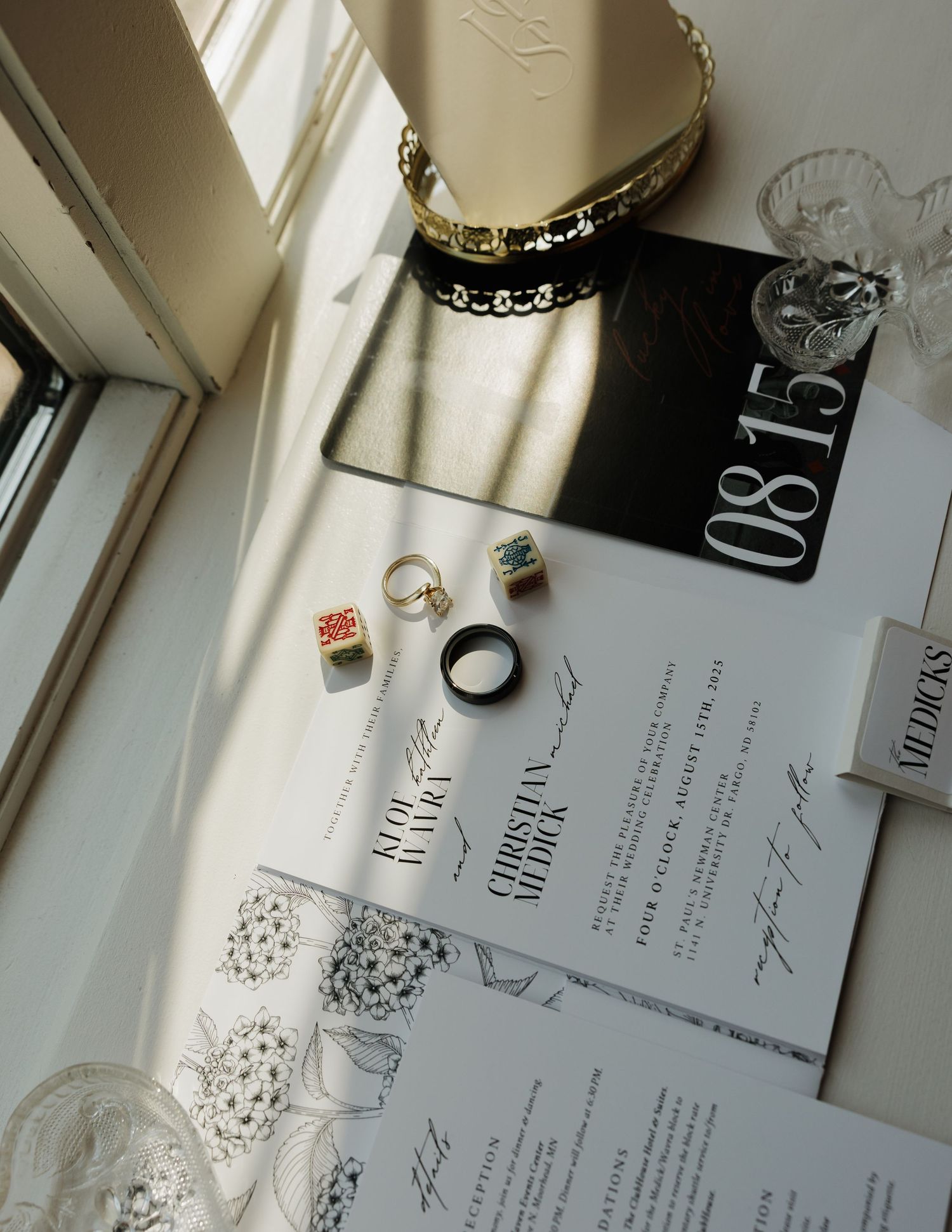 Jewelry and paper items arranged in a minimalist flat lay composition near a window with natural light.