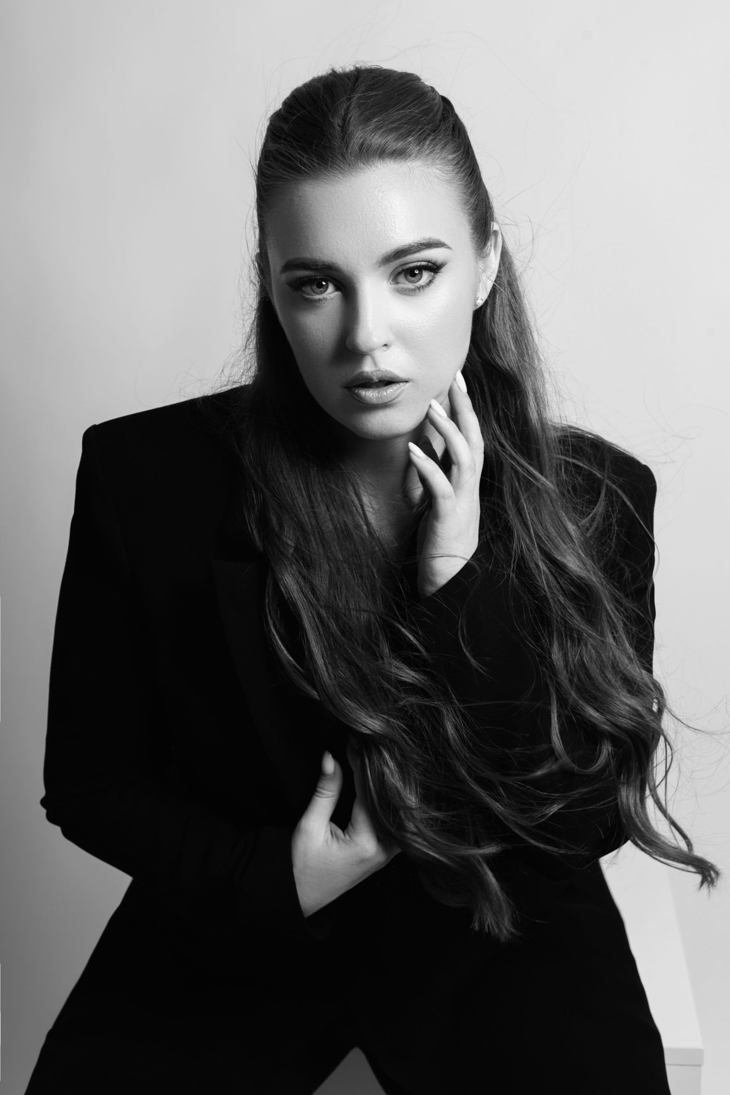 Dramatic black and white fashion portrait with long dark hair and bold makeup.