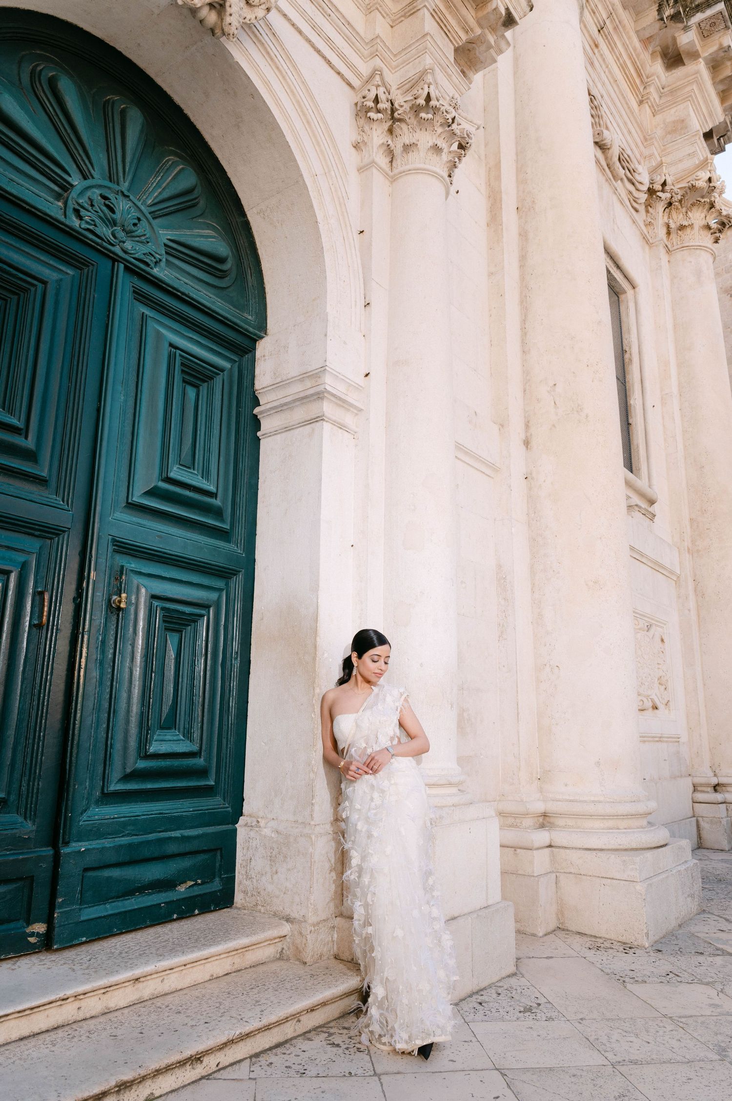 A historic church entrance with ornate turquoise doors and white stone architecture.