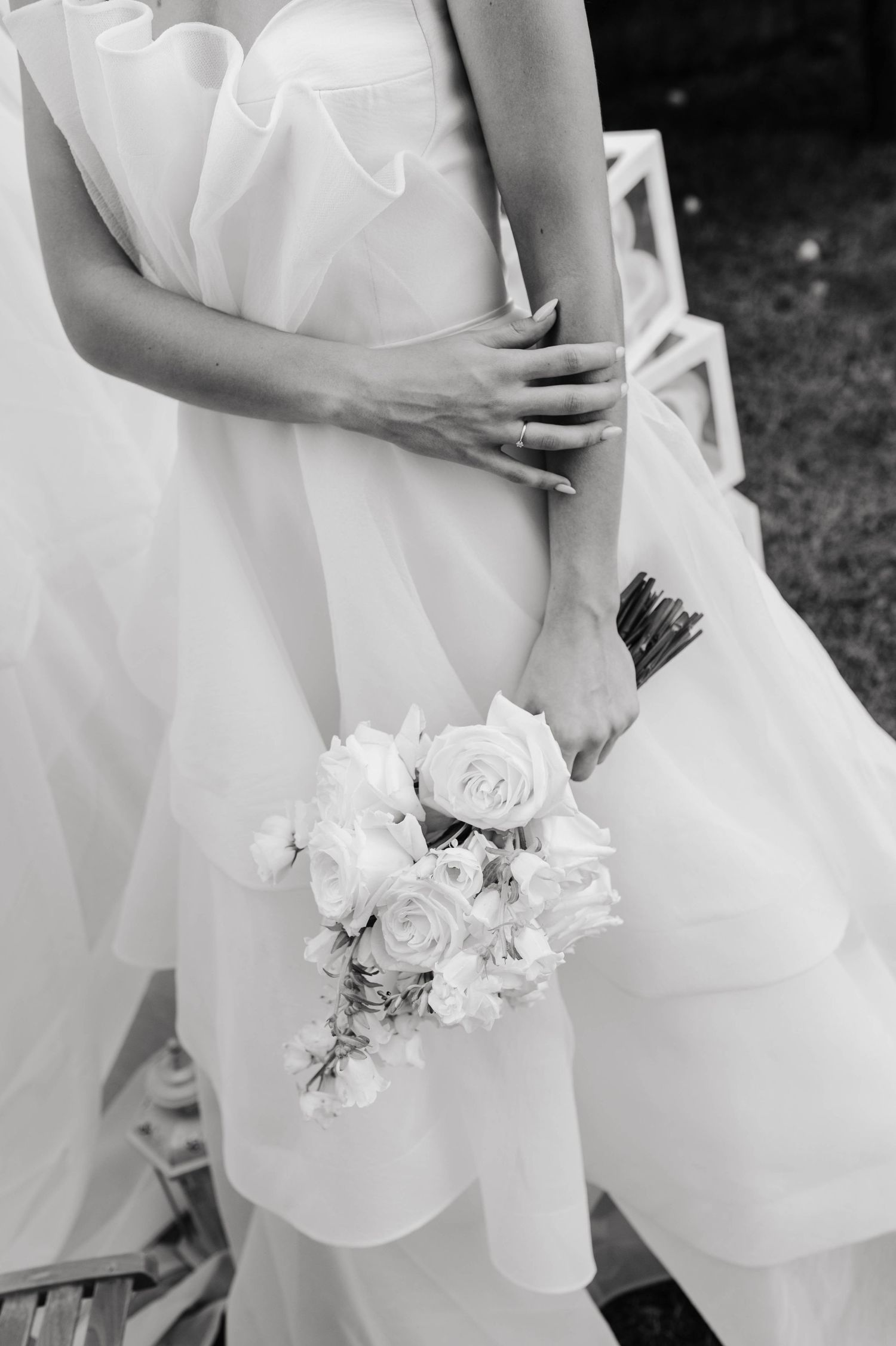 A delicate white bouquet with roses rests against flowing fabric in black and white.