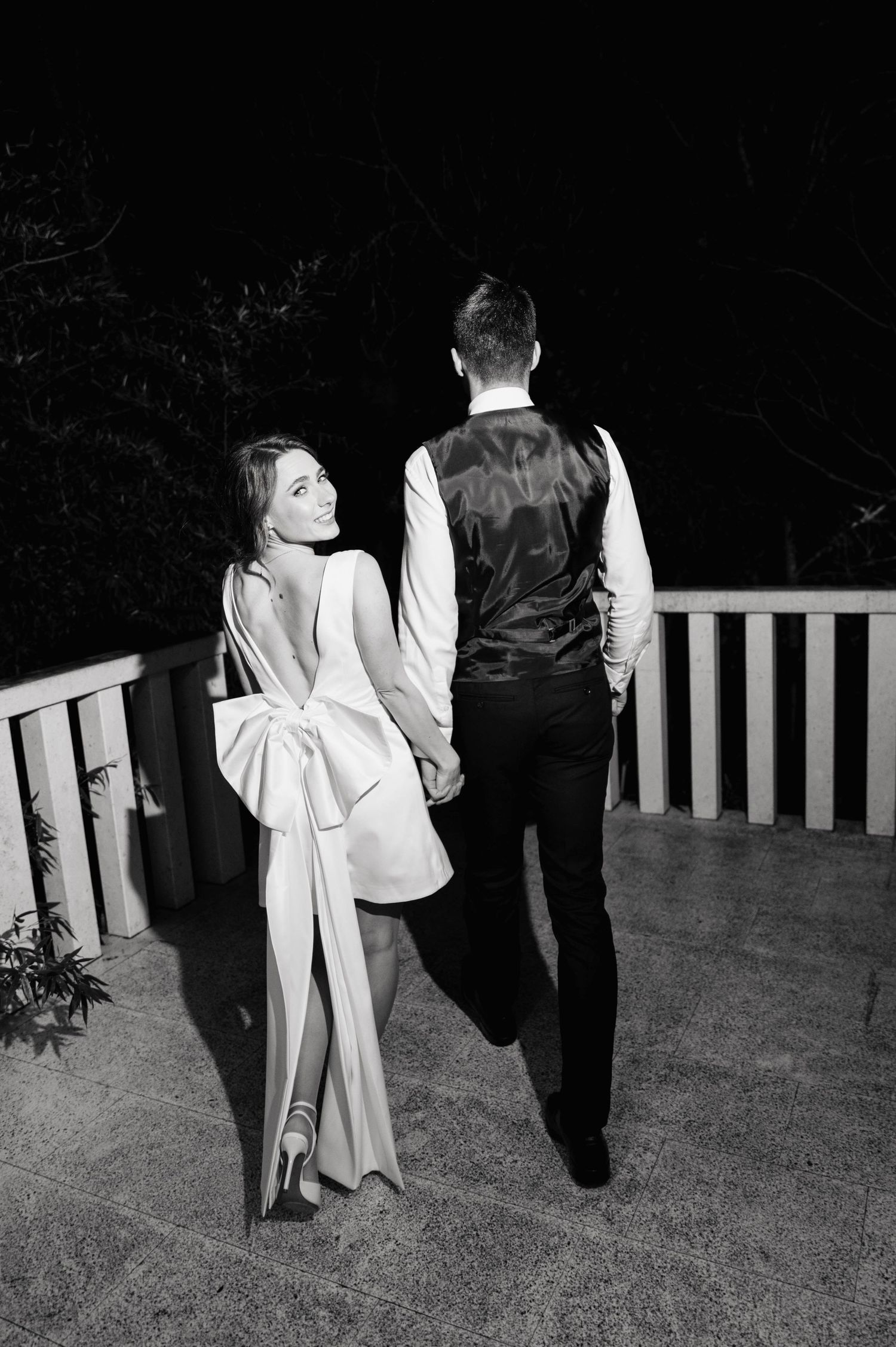 Black and white nighttime portrait of couple in formal attire on outdoor deck.