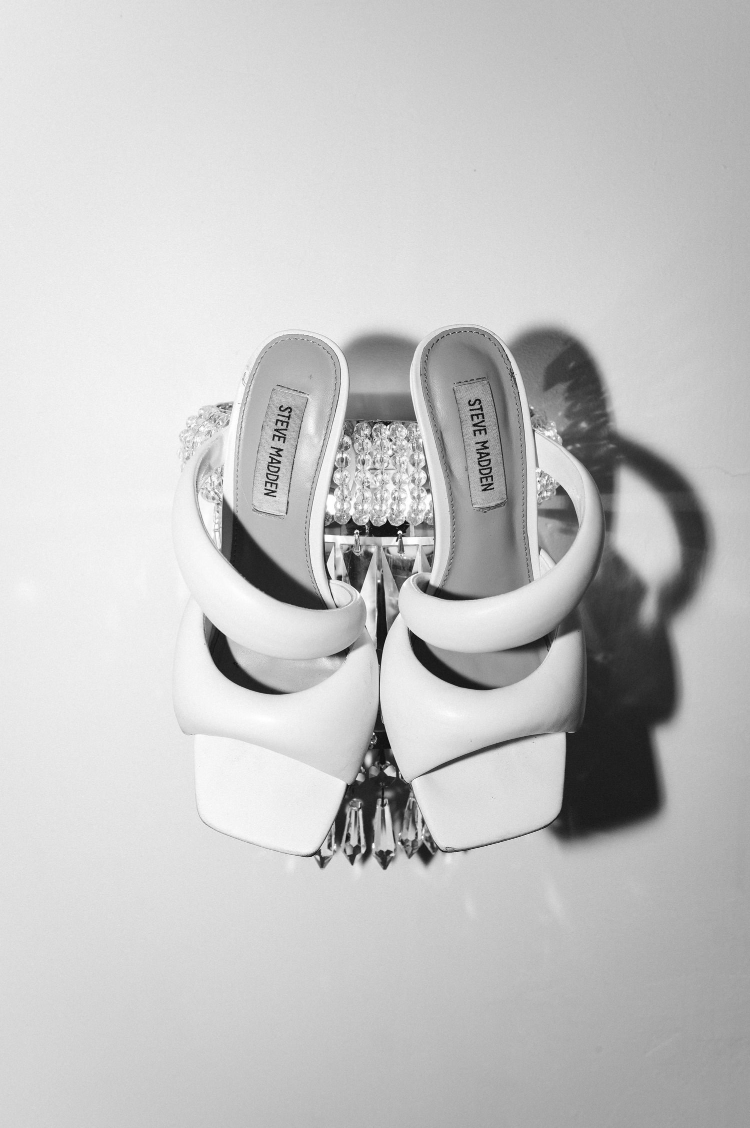 White Steve Madden sandals with jewelry accessories in black and white photography.