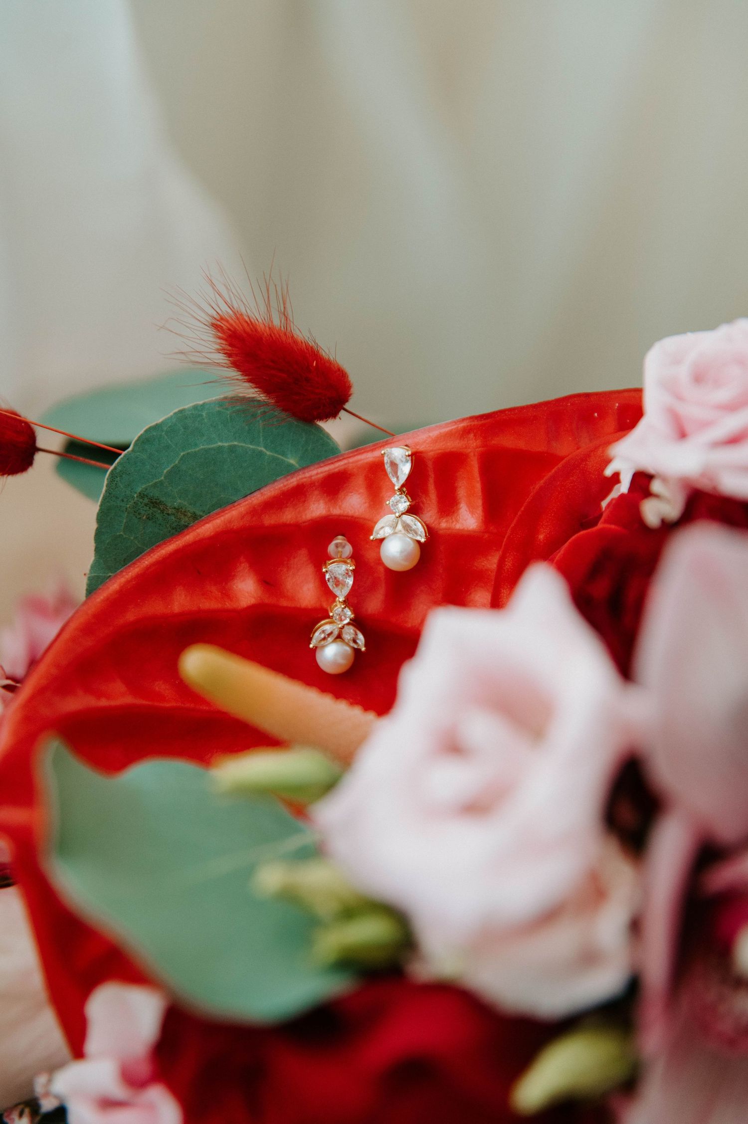 Red and white floral arrangement with delicate crystal details and green foliage.