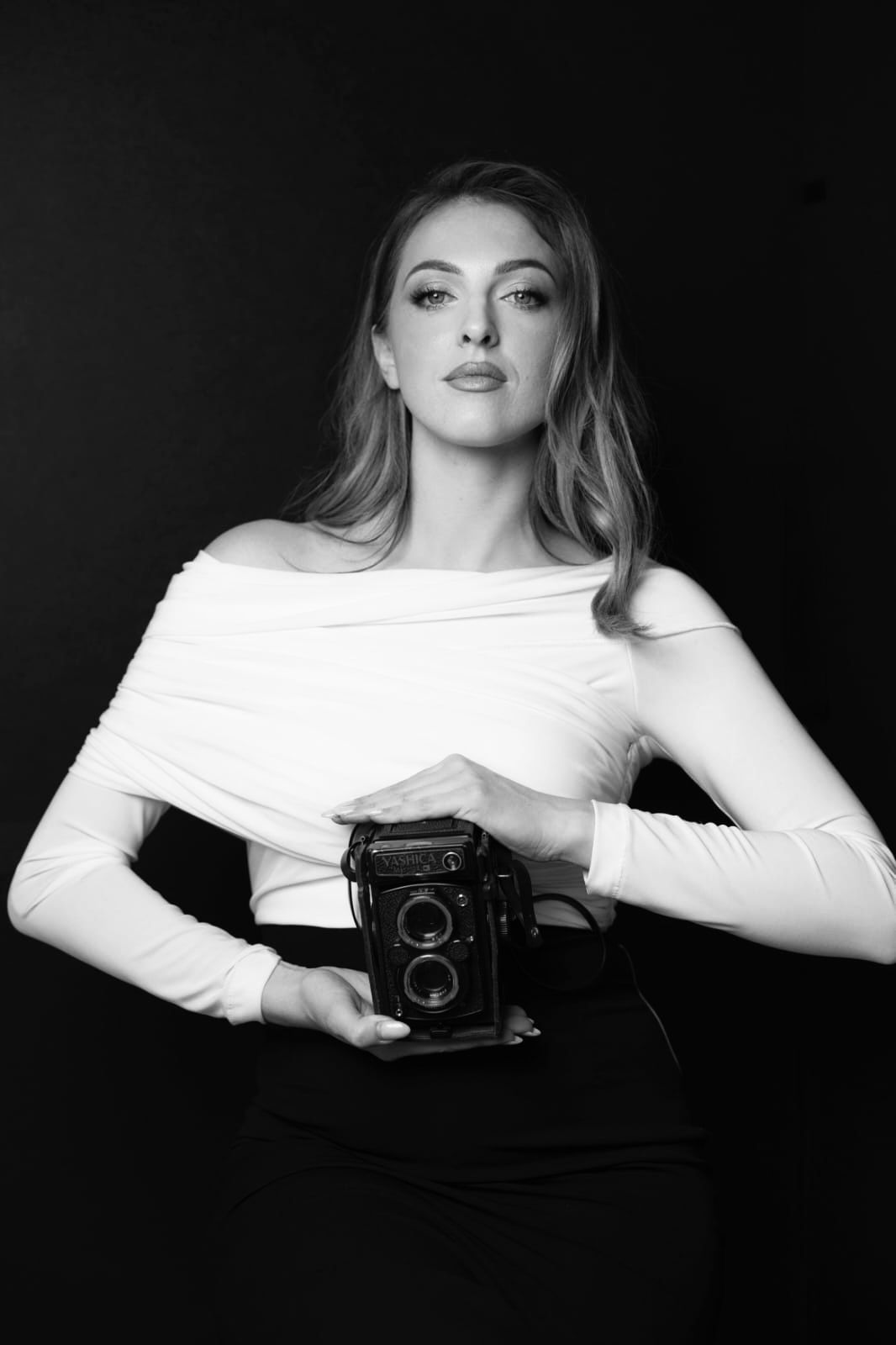 Classic black and white portrait featuring vintage camera and elegant styling.