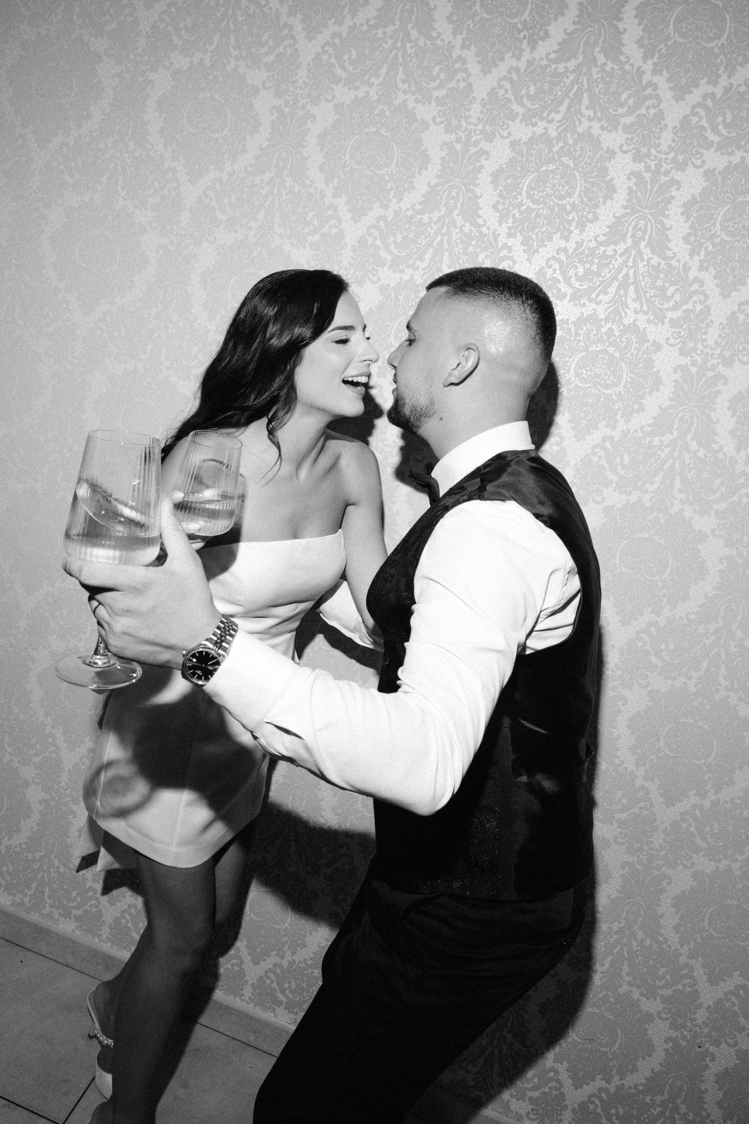 Black and white photo series showing a couple dancing and sharing romantic moments against a textured wall background.