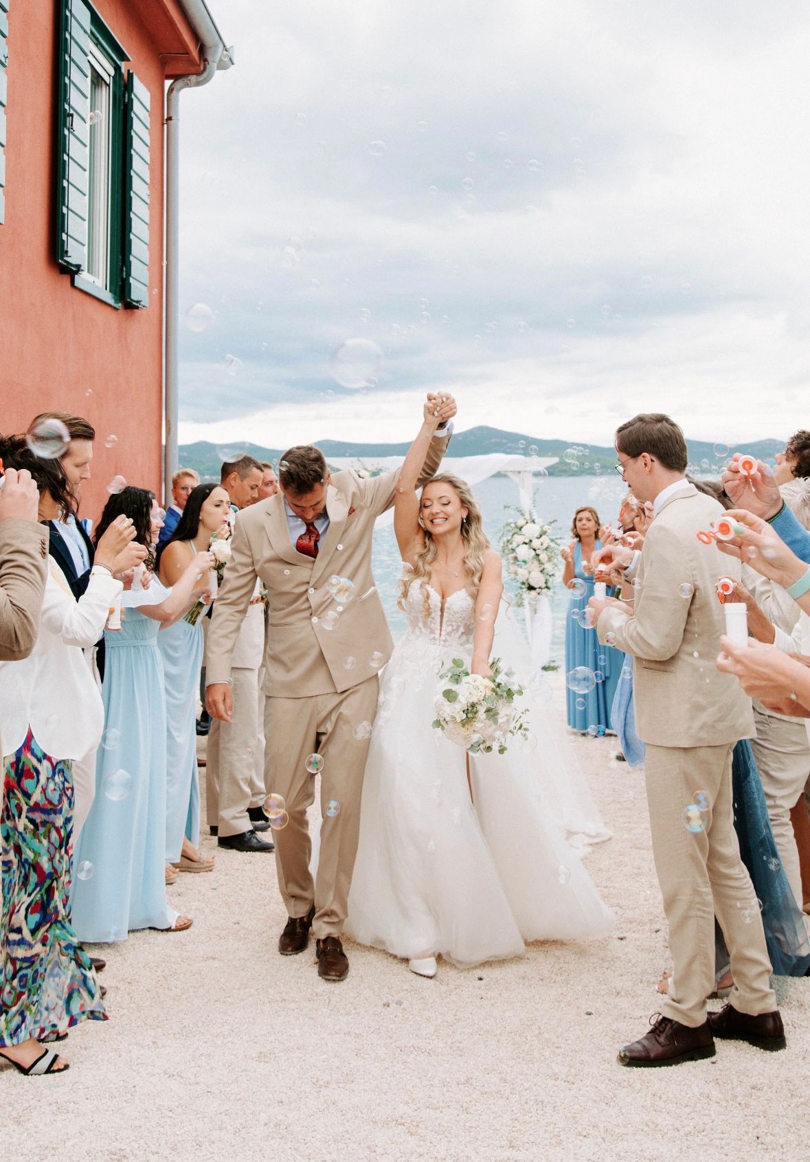 Joyful wedding celebration outside a coral-colored building with mountain views.