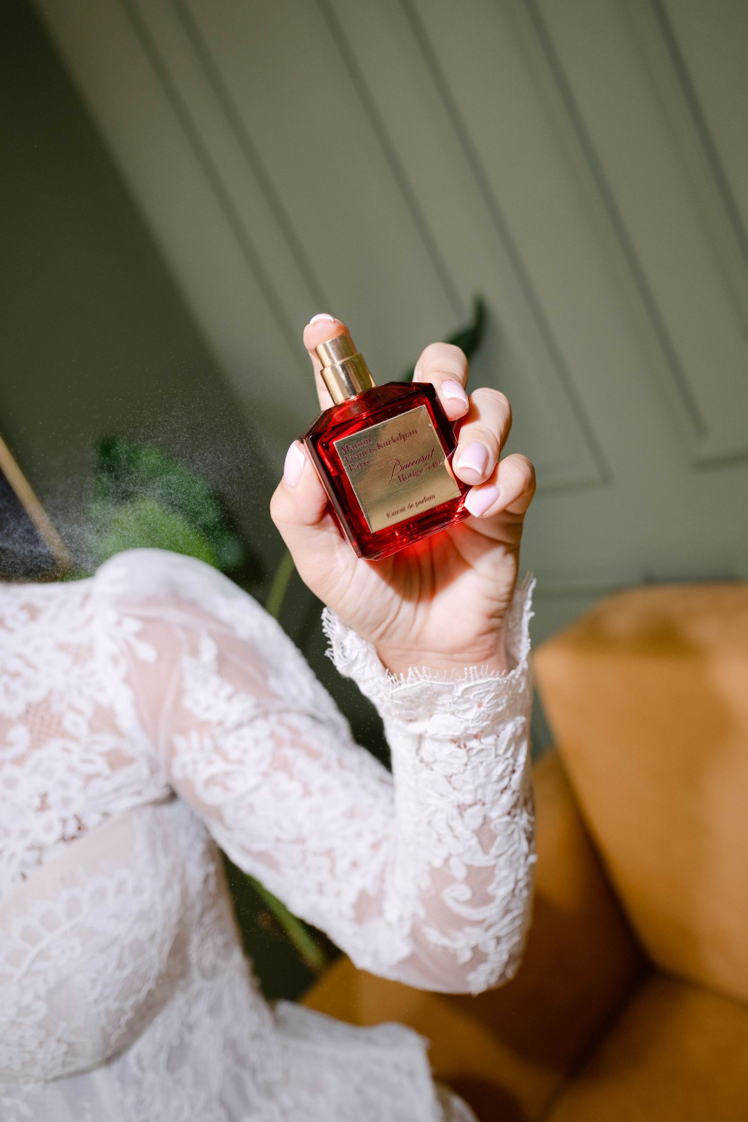 Bride in lace dress spraying red Maison Francis Kurkdjian Baccarat Rouge 540 perfume bottle.