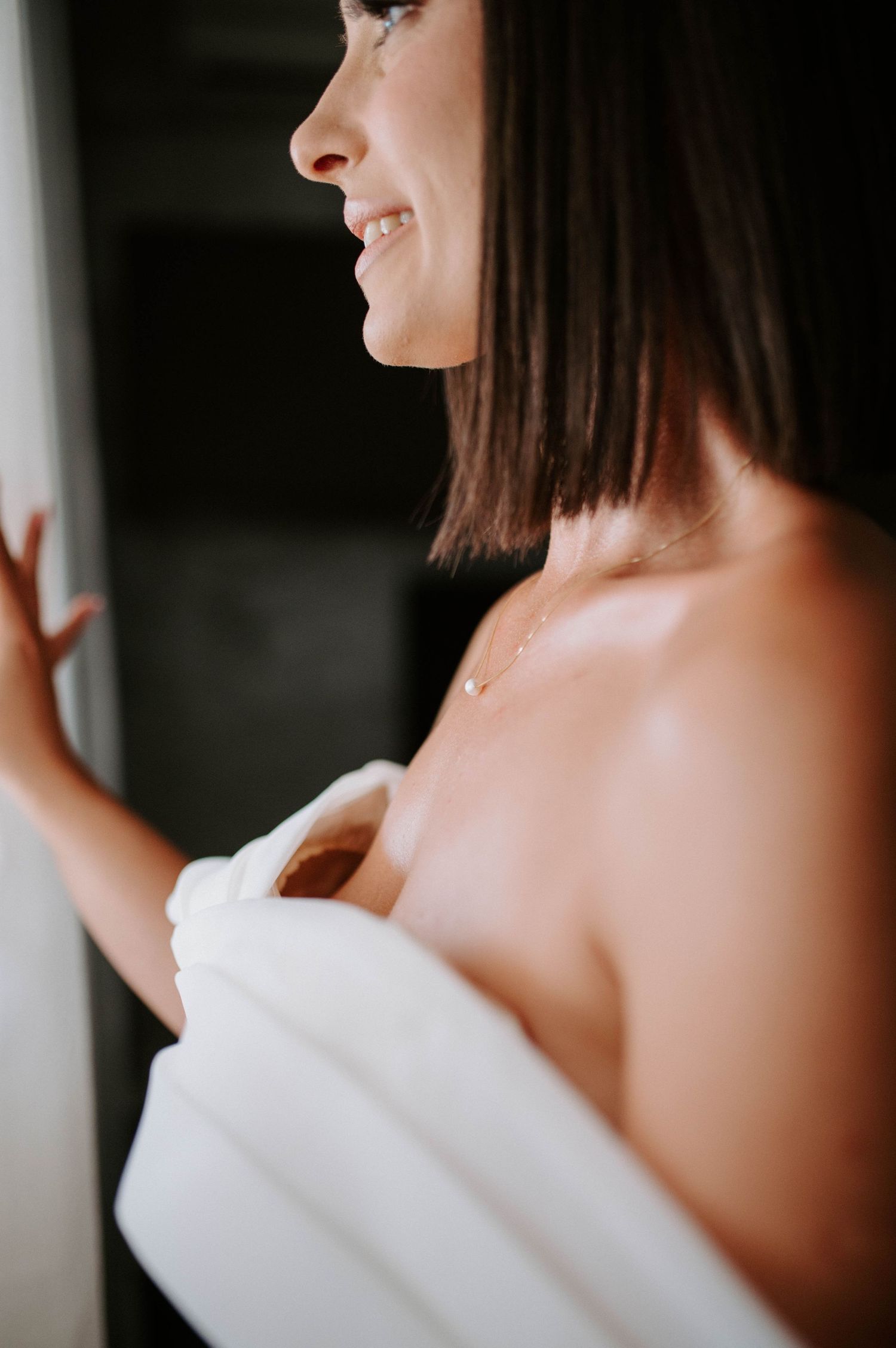 A side profile portrait of a bride getting ready in natural window light.