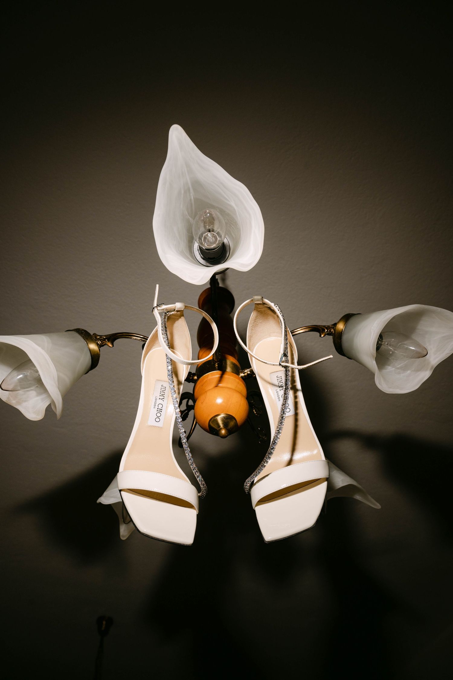 Wedding shoes photographed in a creative sequence showing white heels against a dark background.