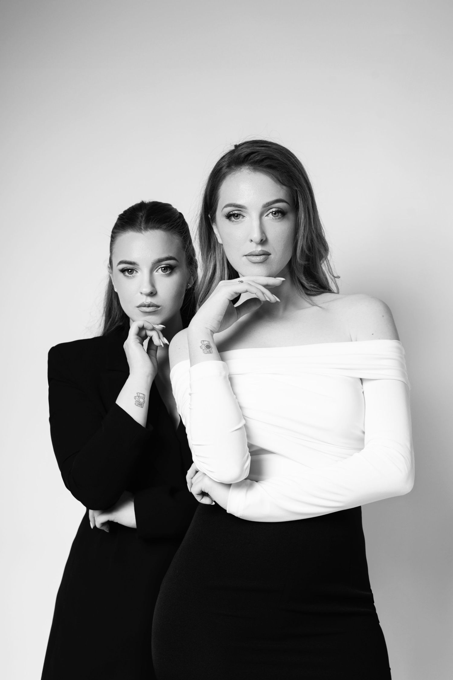 Studio portrait of two models in contrasting black and white outfits against a light background.