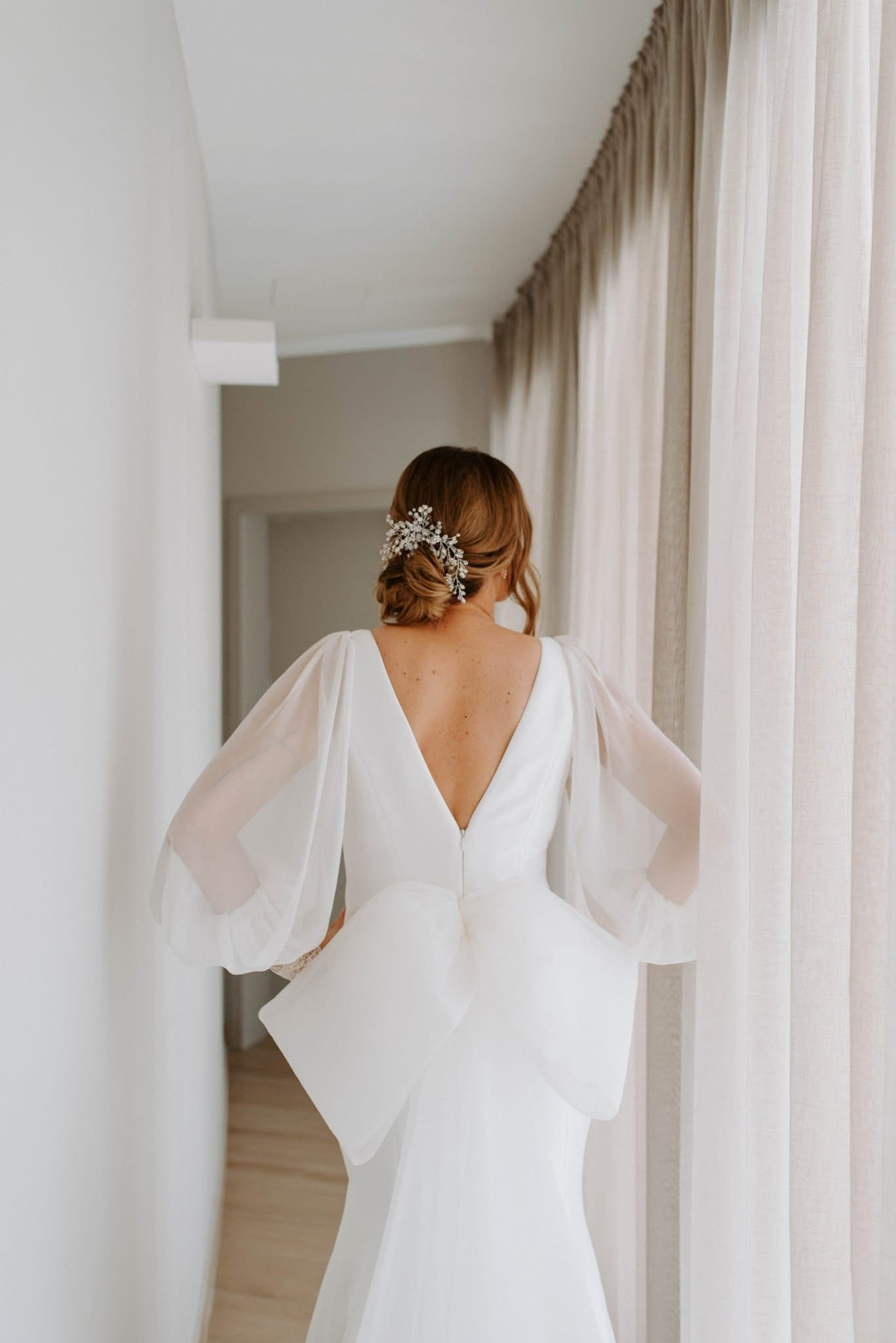 Back view of a modern wedding dress with sheer balloon sleeves and V-back detail.