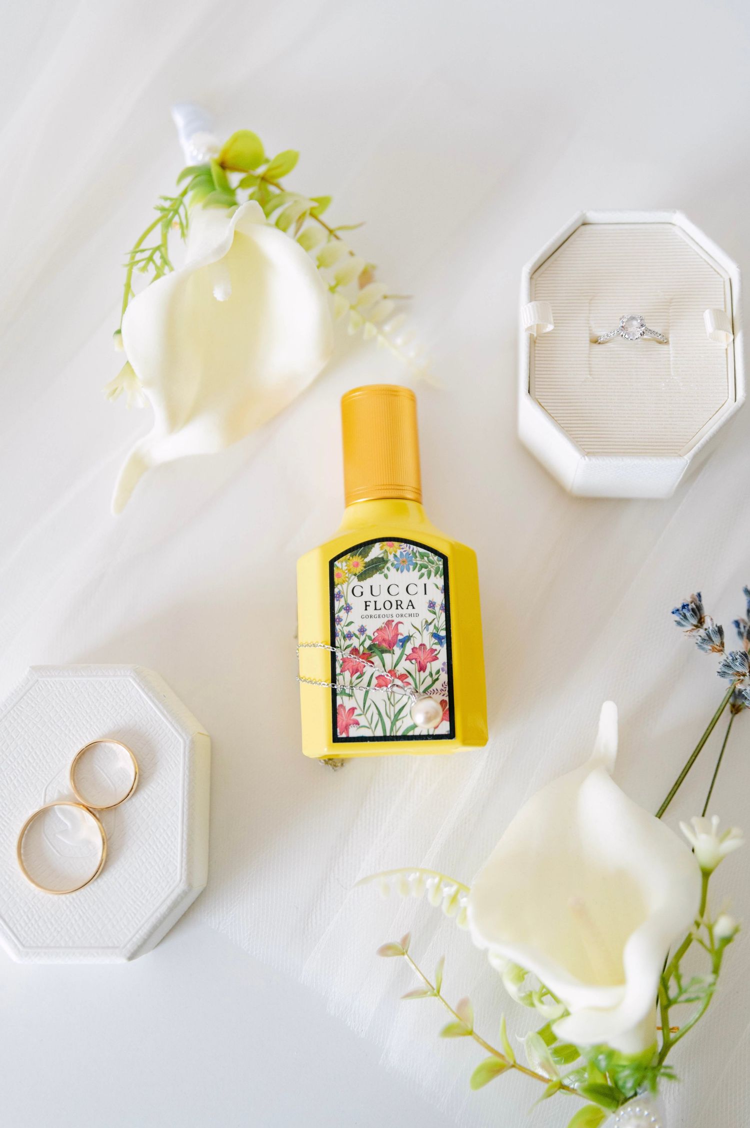 Minimalist flatlay composition with yellow honey bottle, white octagonal dishes, and delicate green foliage on light background.