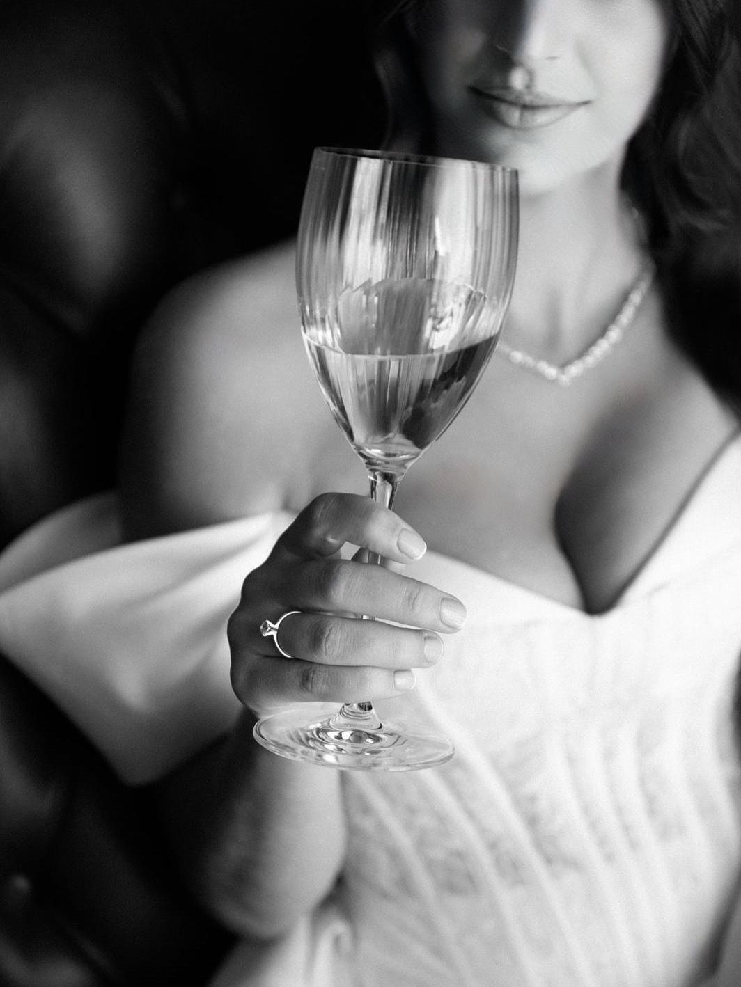 Black and white close-up photos of a wine glass being held in an elegant white dress setting.