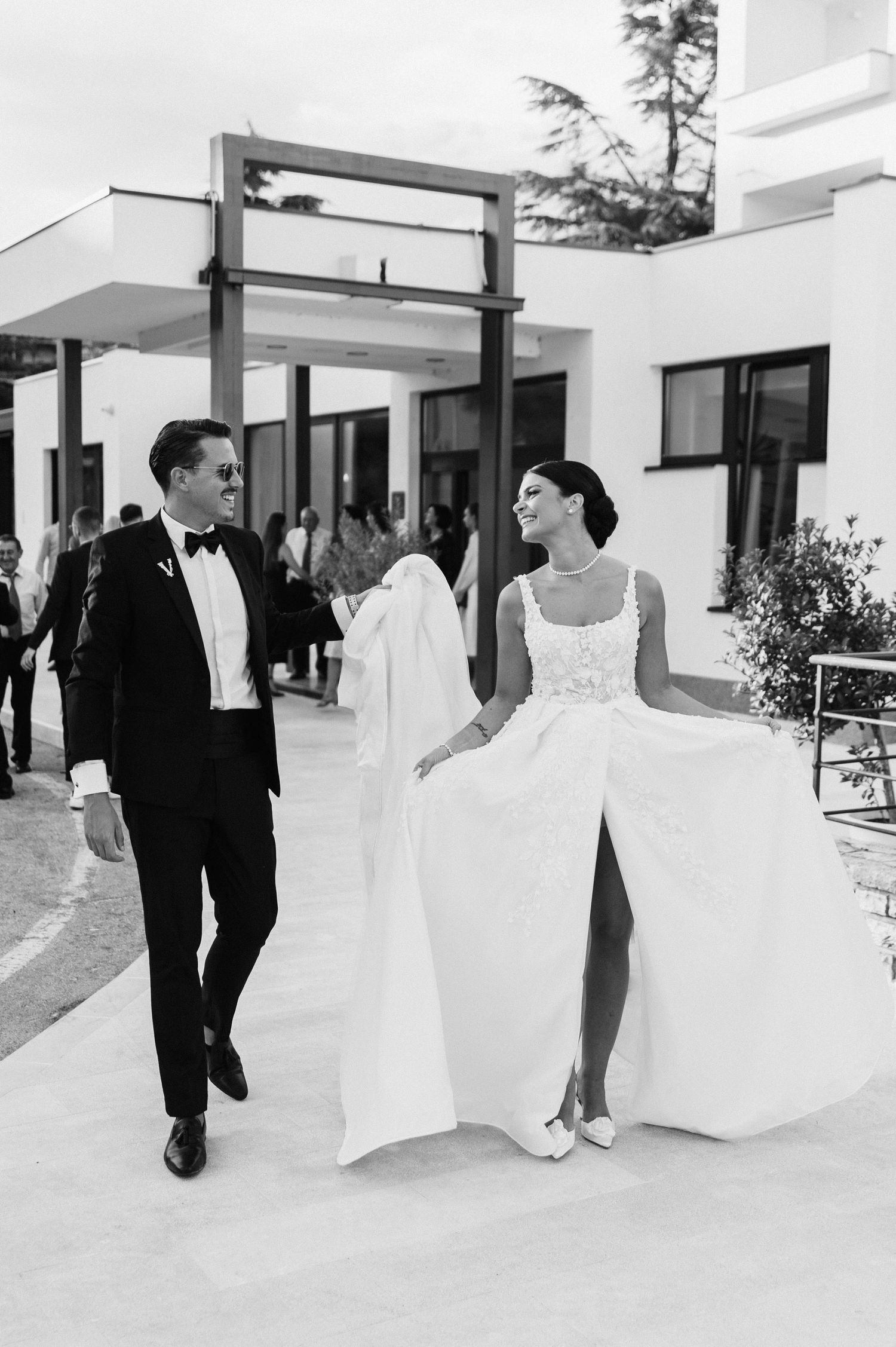 Elegant wedding couple walking together outdoors in formal black and white attire.