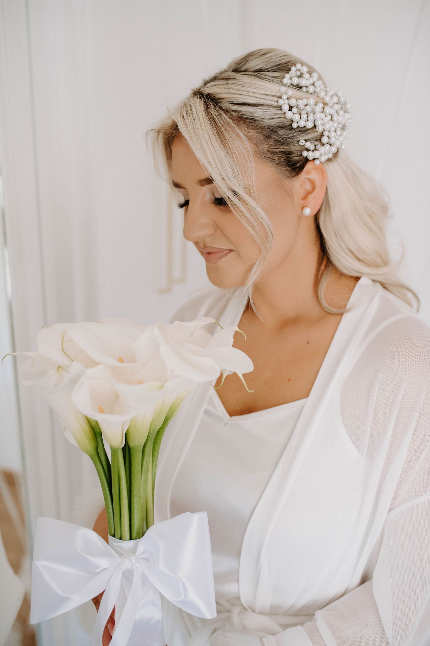 Bridal portrait with white calla lily bouquet and pearl hair accessory.