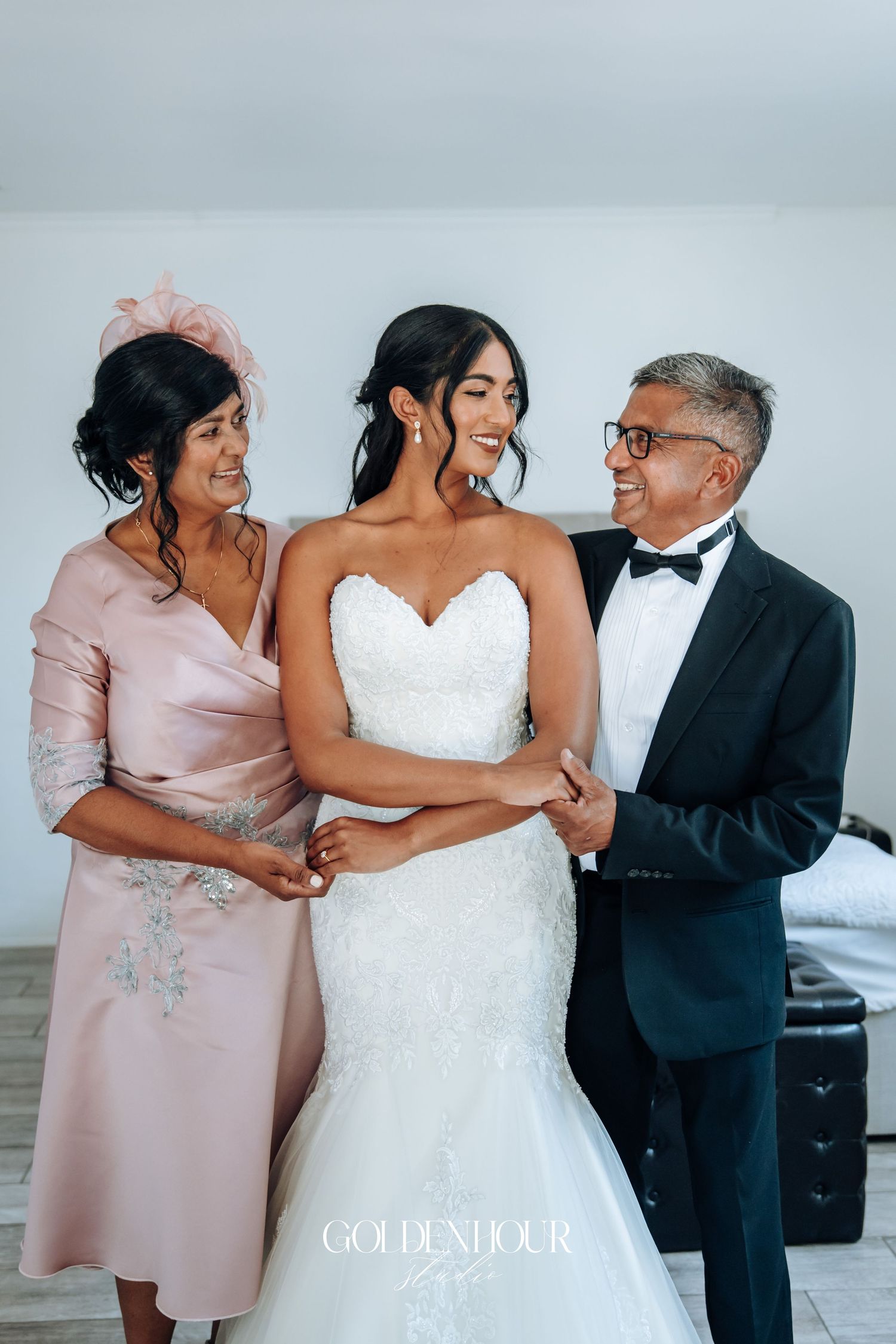 Wedding party members share a joyful moment in formal attire including a white bridal gown and pink dress.
