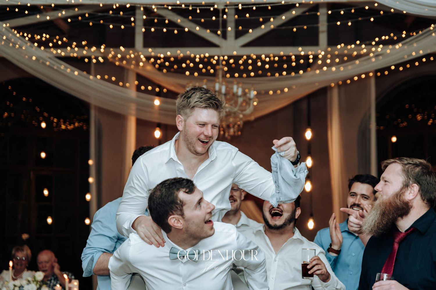 Celebration scene with string lights and dancing at indoor wedding reception.