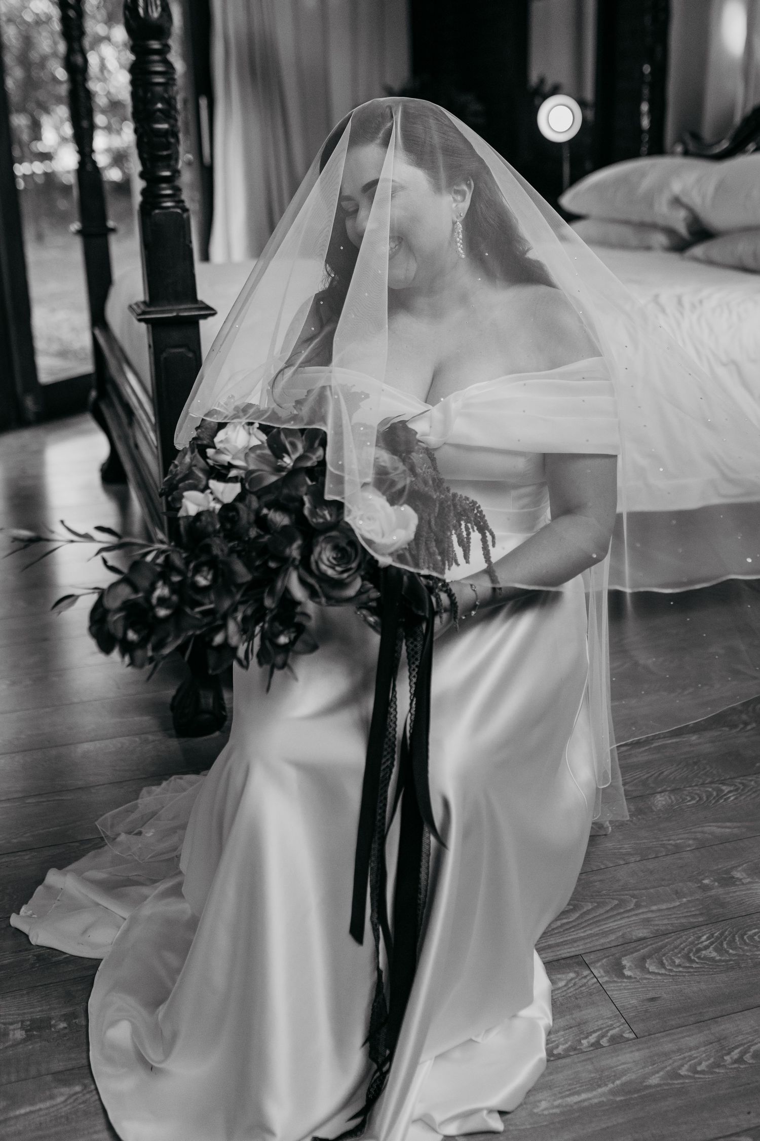 Black and white image of flowing white wedding dress details and dark floral accents.