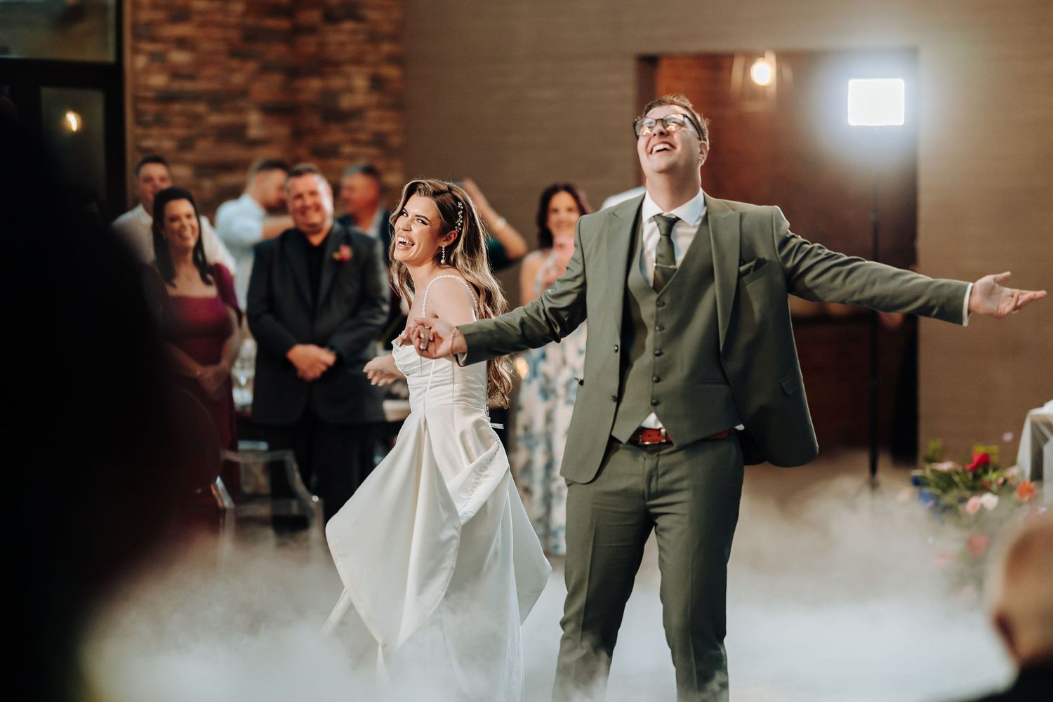 Wedding guests dancing and celebrating on a dance floor at an indoor reception.