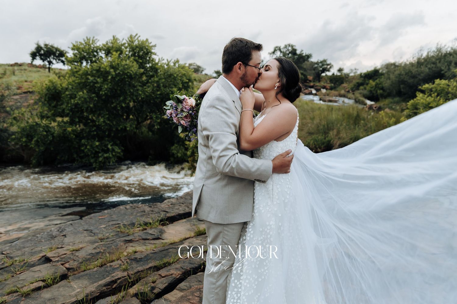 Romantic wedding portraits on rocky terrain with flowing white dress and veil.