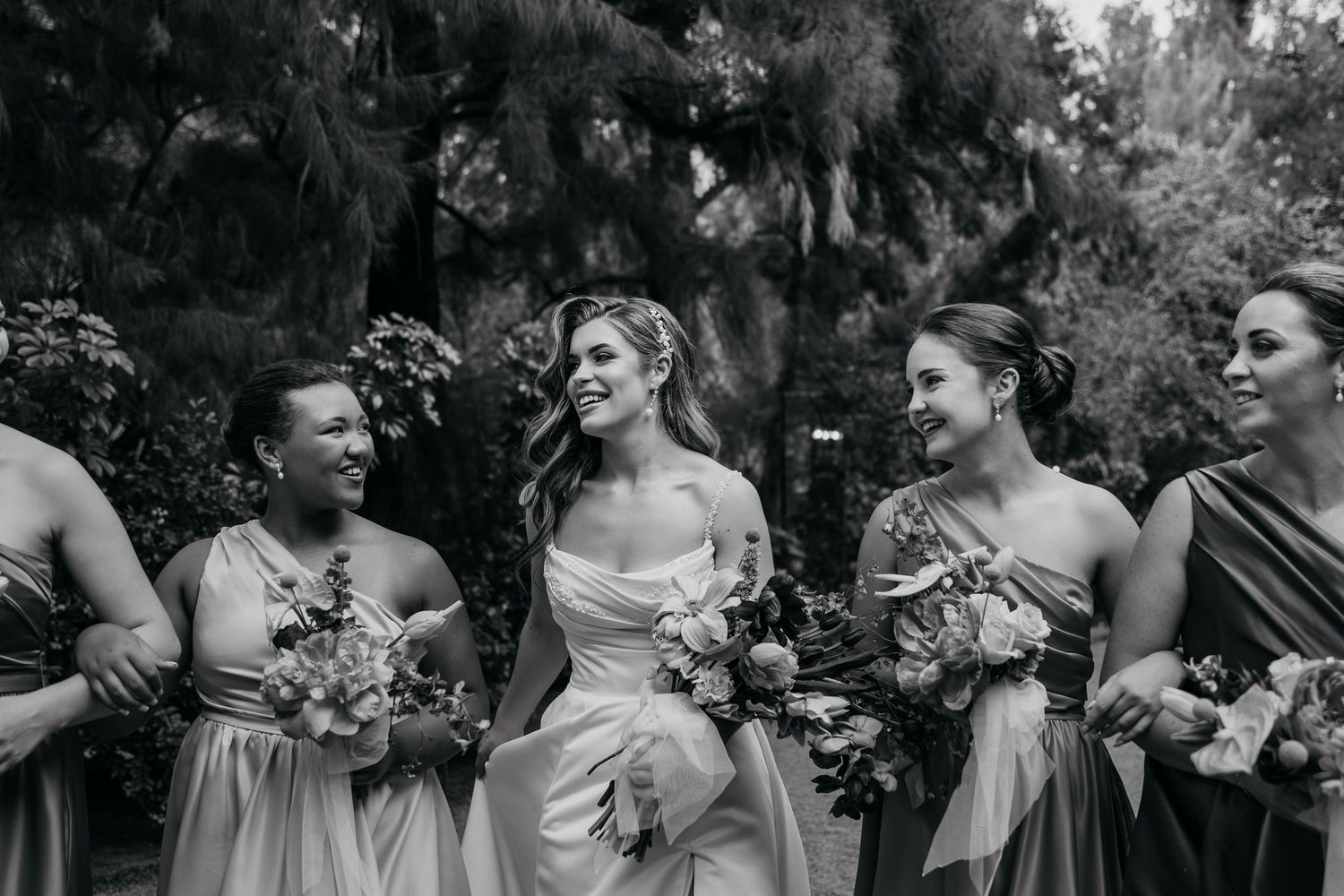 Black and white wedding party candid photos showing joyful moments and laughter during outdoor celebration.