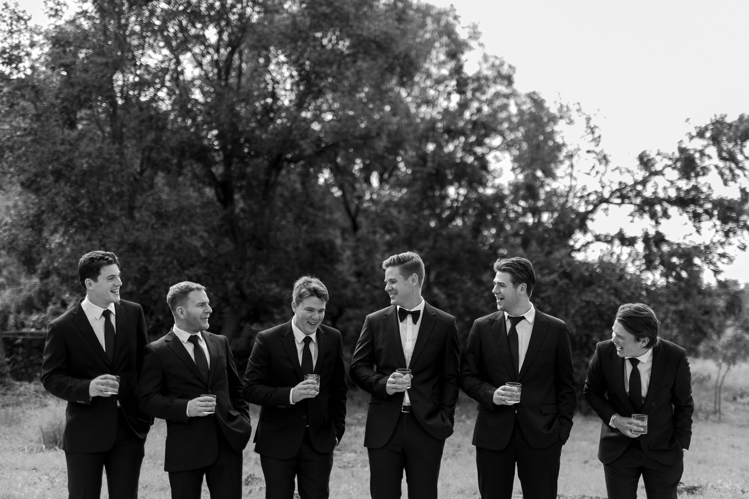 Black and white photo of groomsmen walking together outdoors in formal attire.