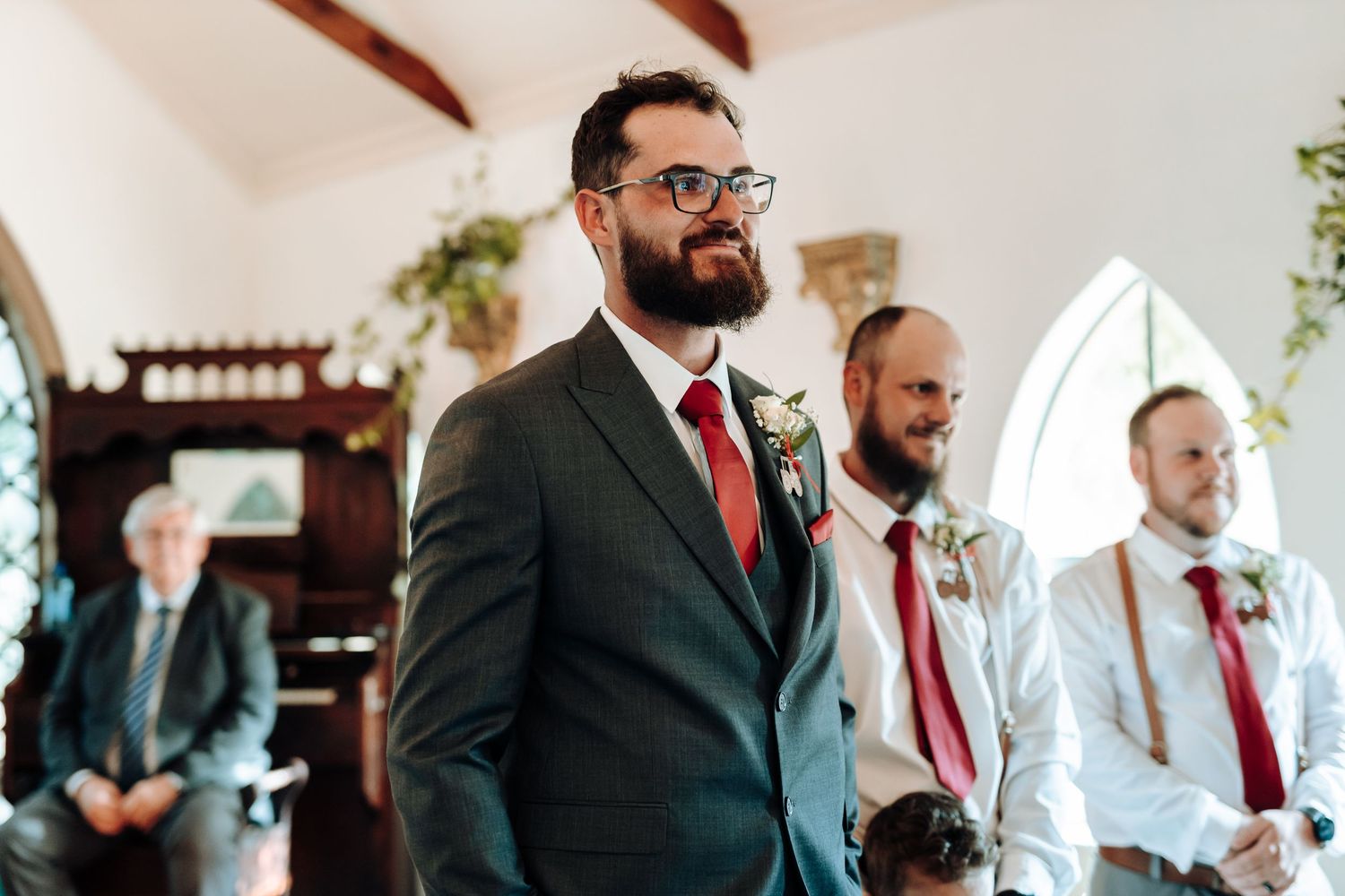 Wedding party members in formal attire standing at the front of a chapel.