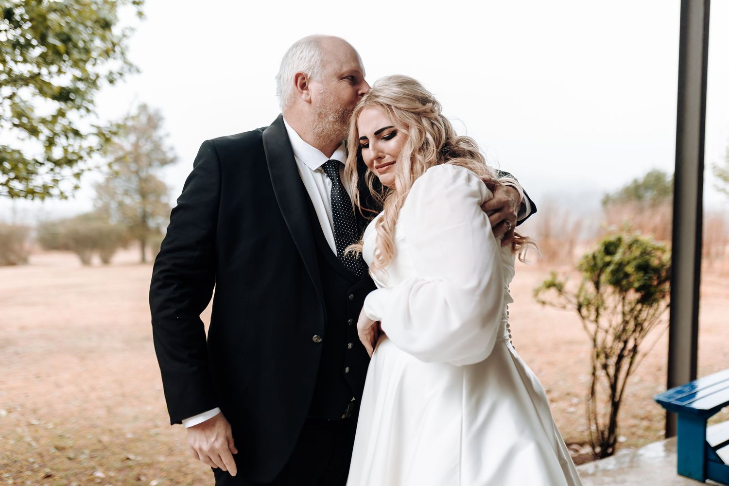 Romantic moment between newlyweds laughing together during outdoor wedding portraits.