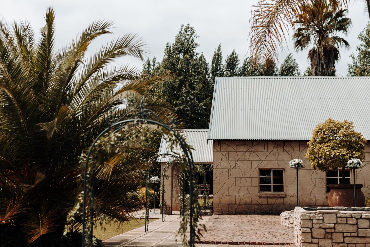 Stone building with palm trees and garden arch entrance creating a tropical ambiance.