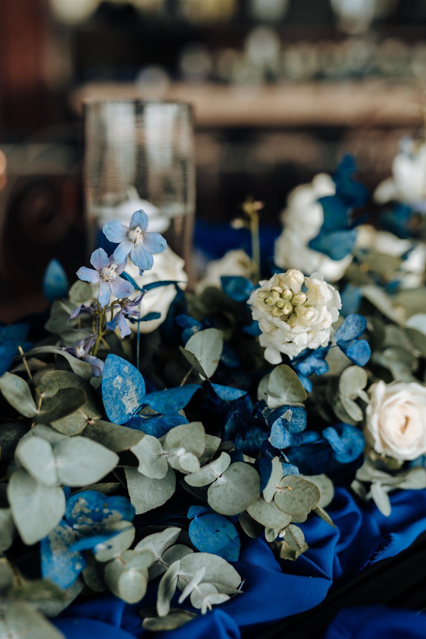 Blue and white floral arrangement with roses and hydrangeas on a dark surface.