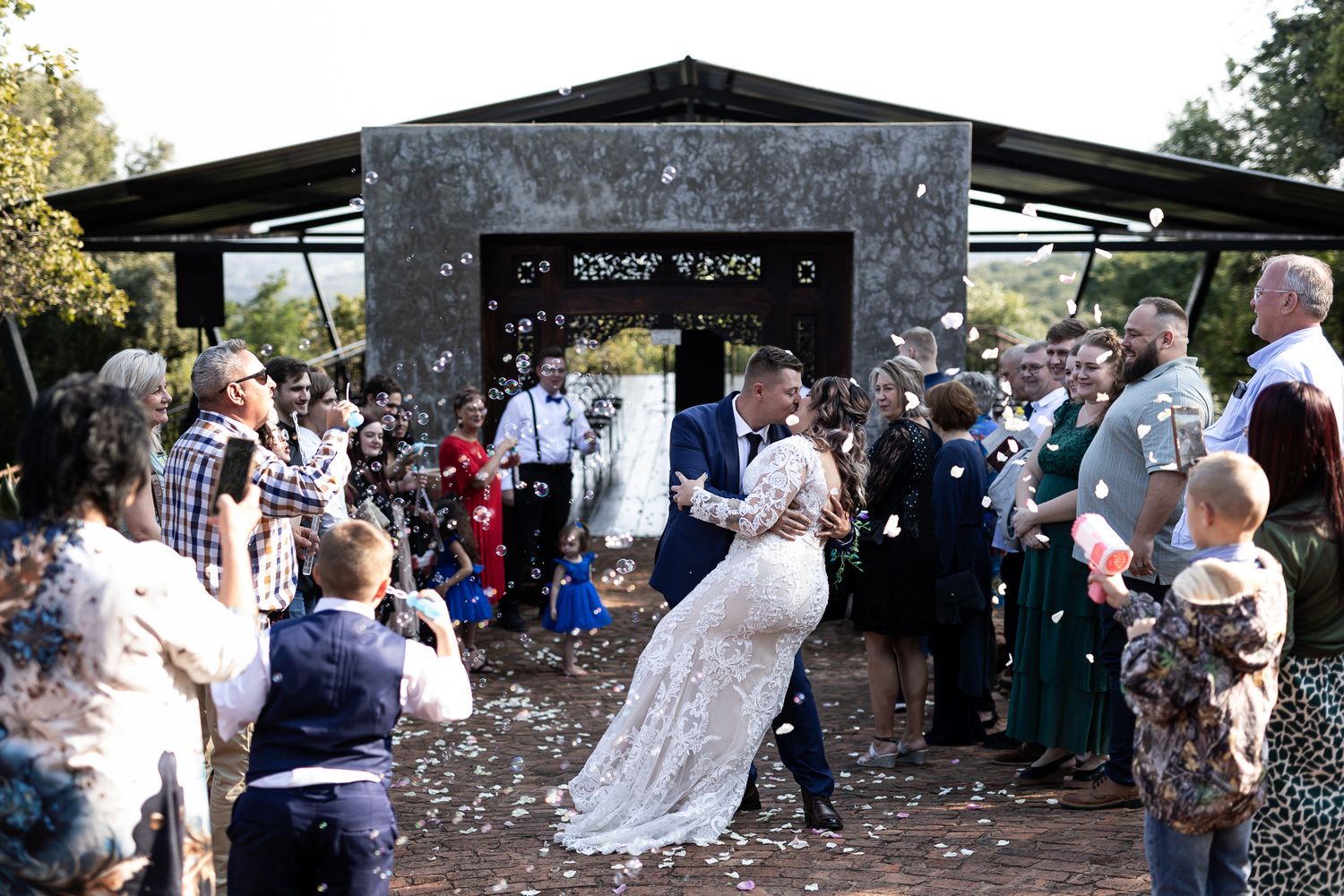 Joyful newlyweds celebrate among shower of confetti at outdoor wedding venue.
