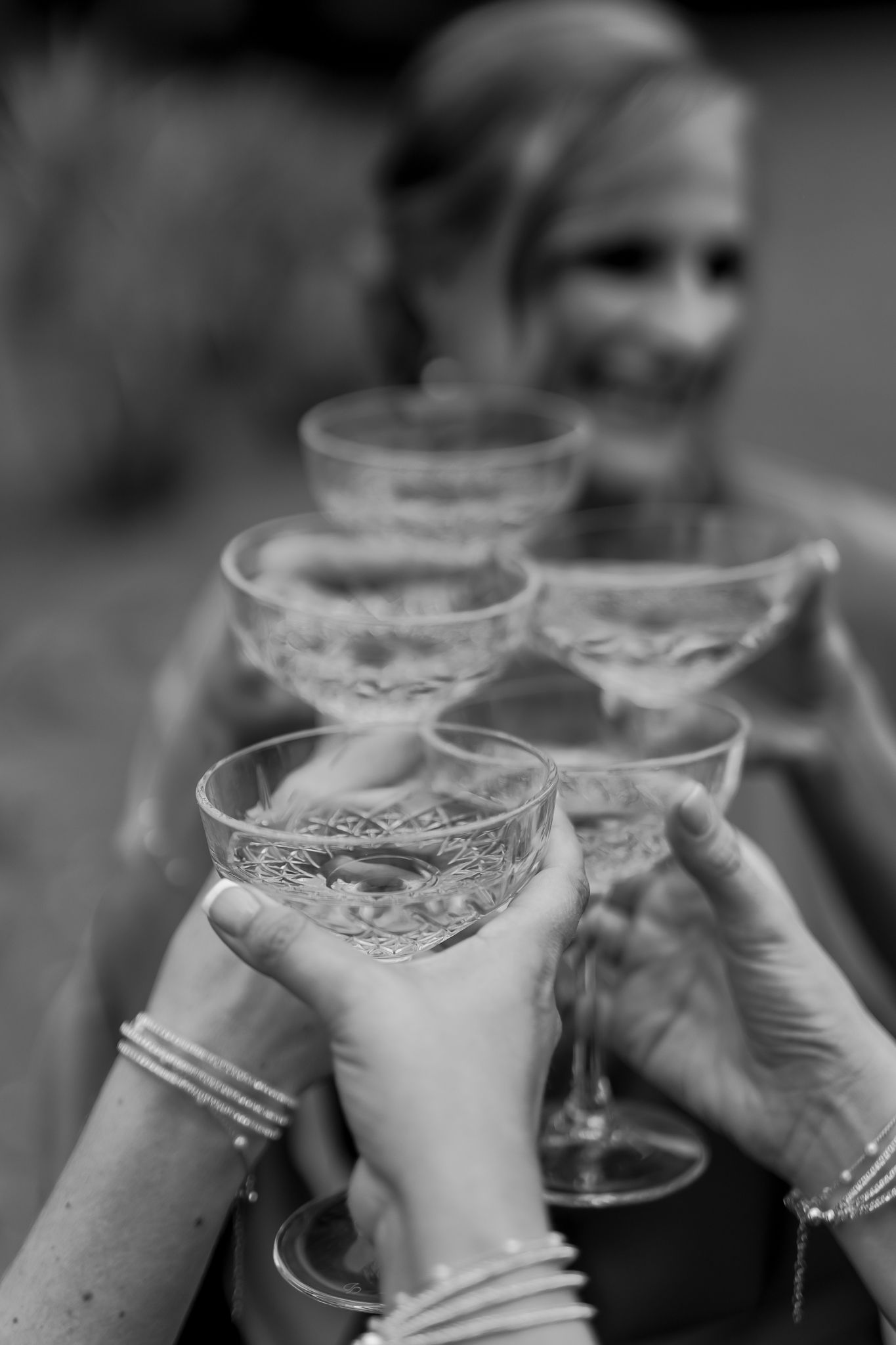 Black and white photo of champagne glasses clinking in a celebratory toast.