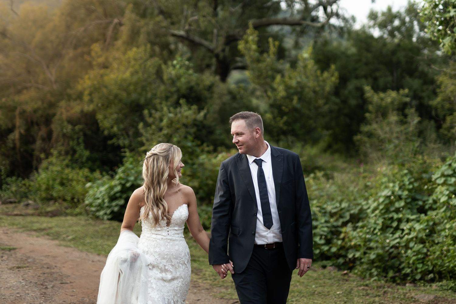 Candid moment of a couple walking together on a rustic outdoor path.