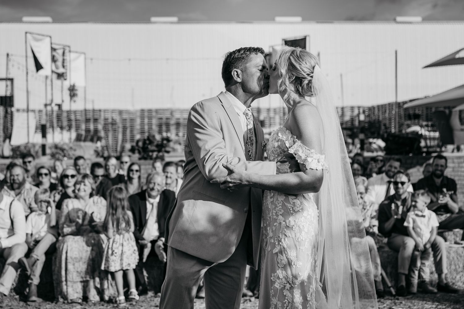 Black and white photo capturing an intimate moment during an outdoor wedding ceremony.