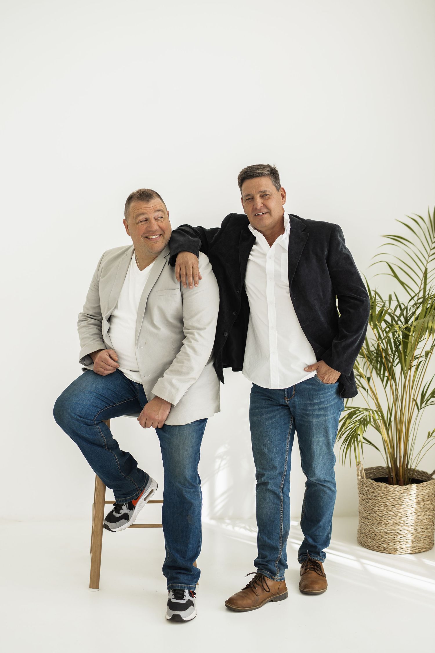 Three artistic portrait poses show a seated model in jeans and white shirt with a companion in a black jacket against white.