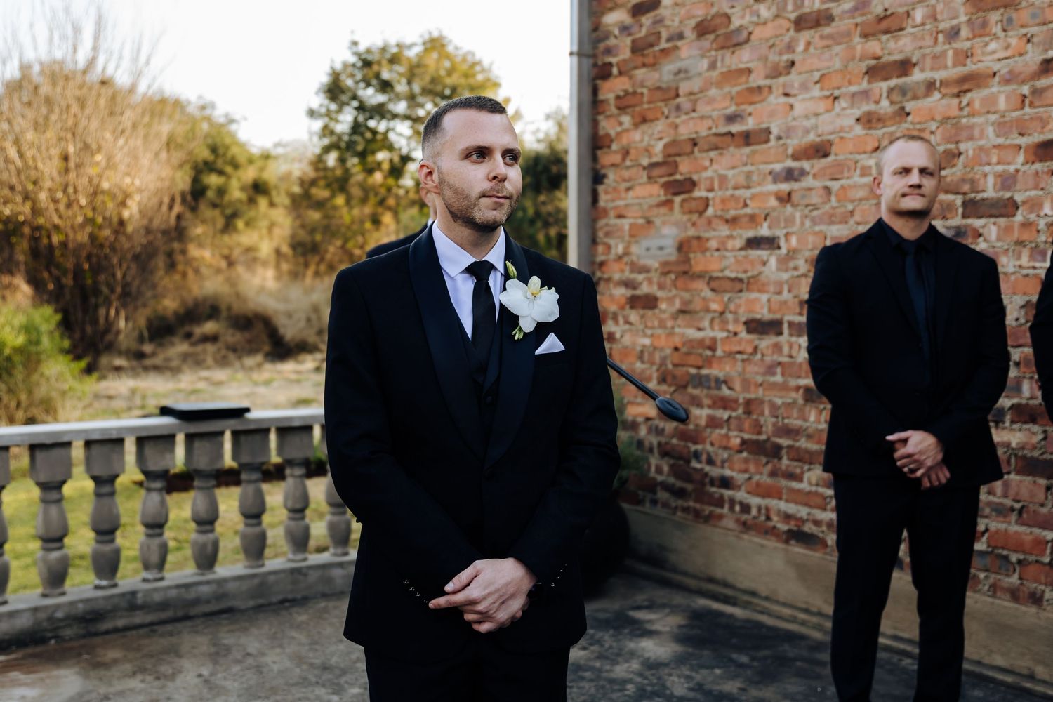 A row of black and white wedding photos against brick walls shows formal wedding party portraits at sunset.