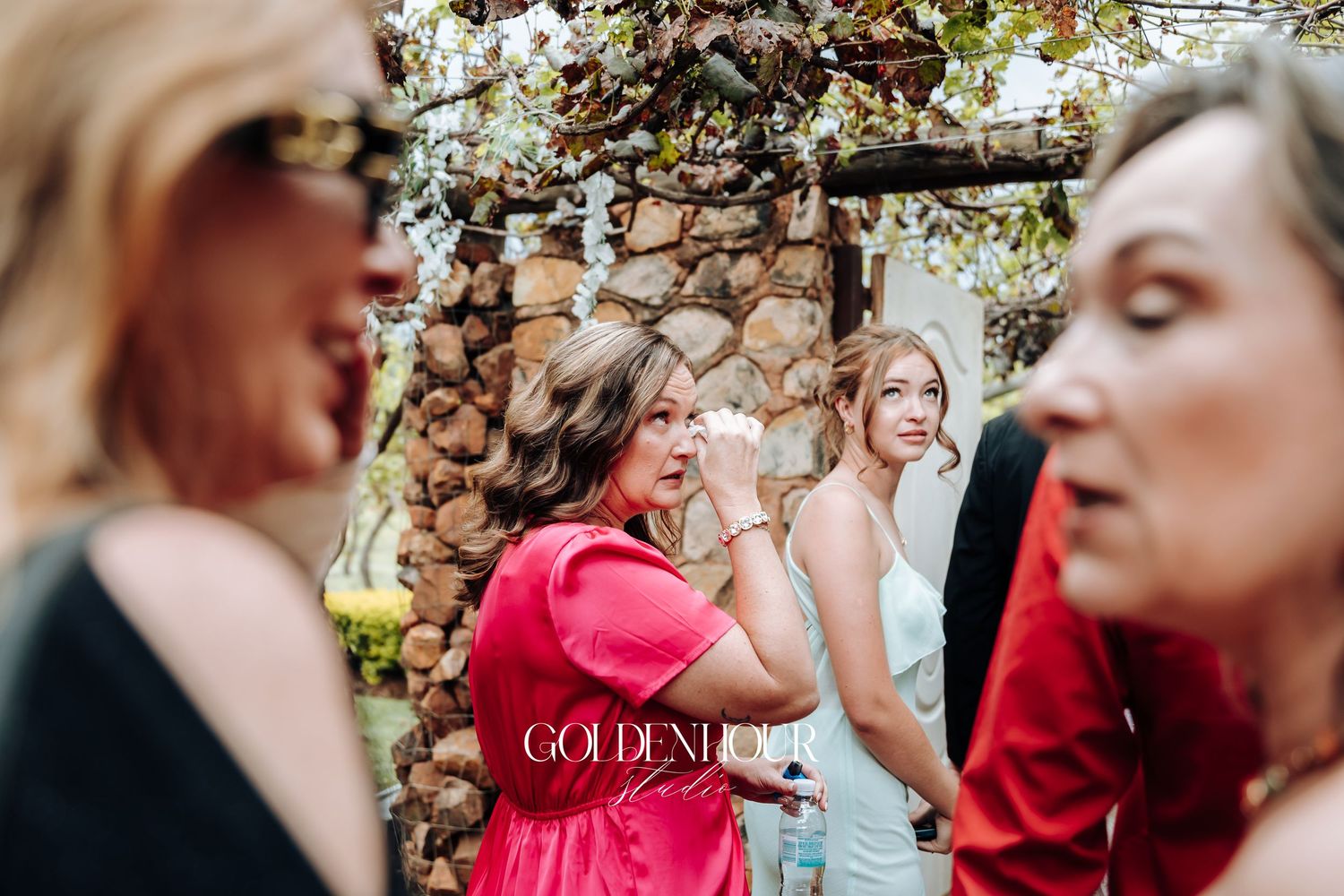 Wedding party shares joyful moment wearing coral colored attire outdoors.