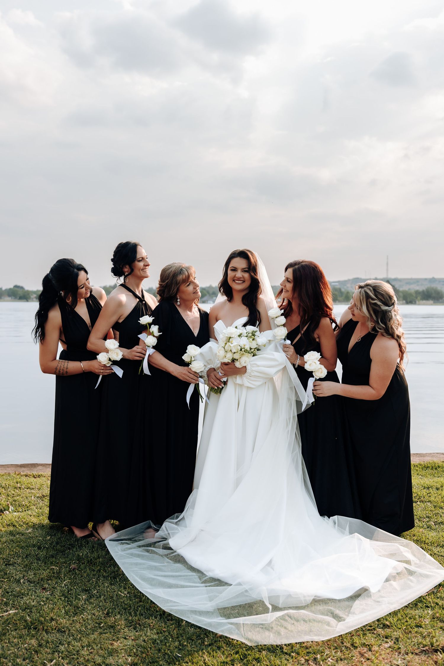 Bridesmaids in black dresses and bride in white gown pose playfully outdoors in a candid photo sequence.